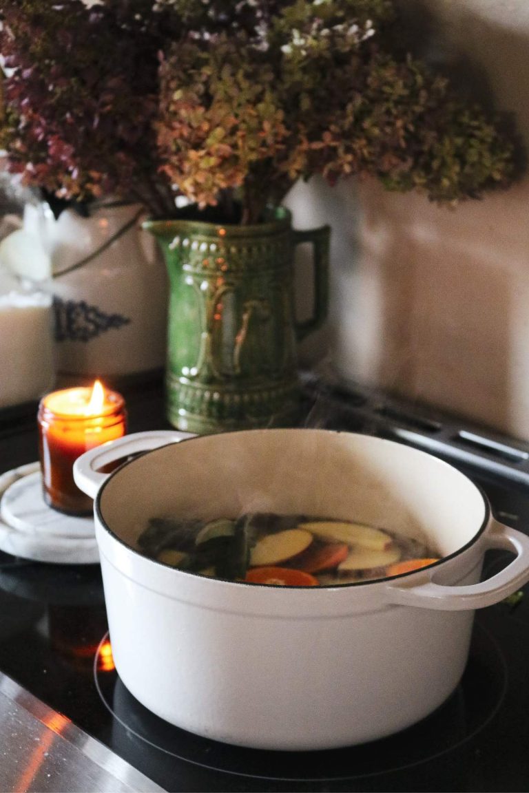 white dutch oven with a fall simmer pot with dried hydrangeas and a candle in the background.
